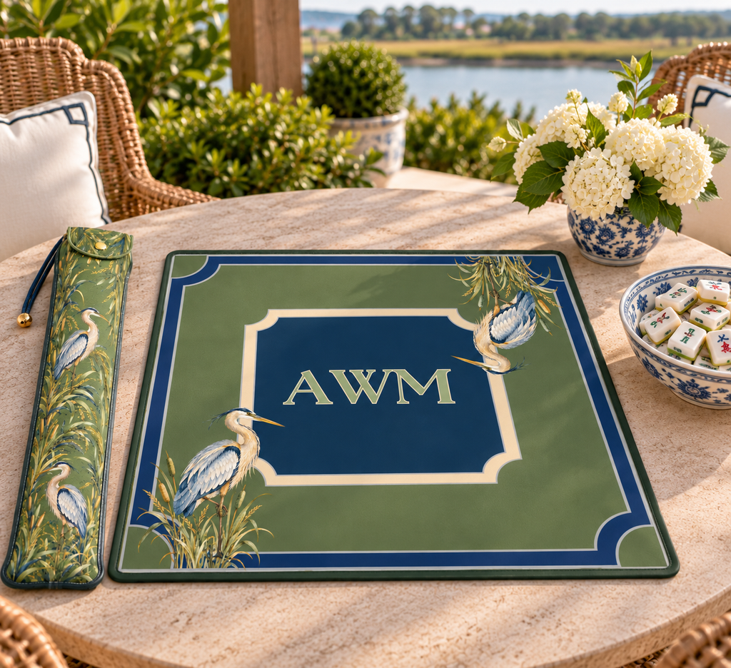 Mahjong mat dust bag, Green with Blue Herons design, shown with a matching monogrammed mahjong mat on an outdoor table by the water
